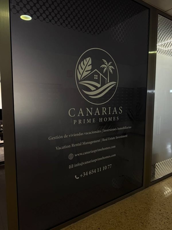 Entrada de la oficina de Canarias Prime Homes con el logotipo en la cristalera